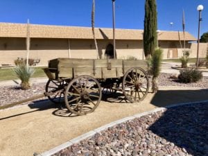 Old horse drawn wagon sitting on dirt surrounded by beautiful desert scenery